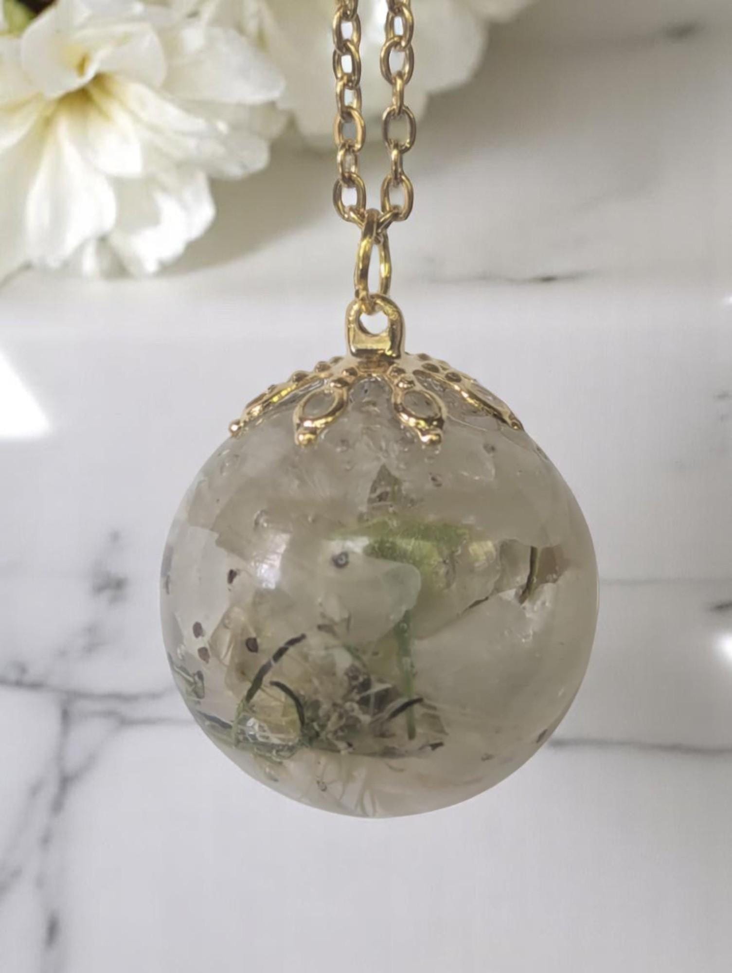 A close up of a dried flower pendant necklace featuring dried bradford pear flower blooms.