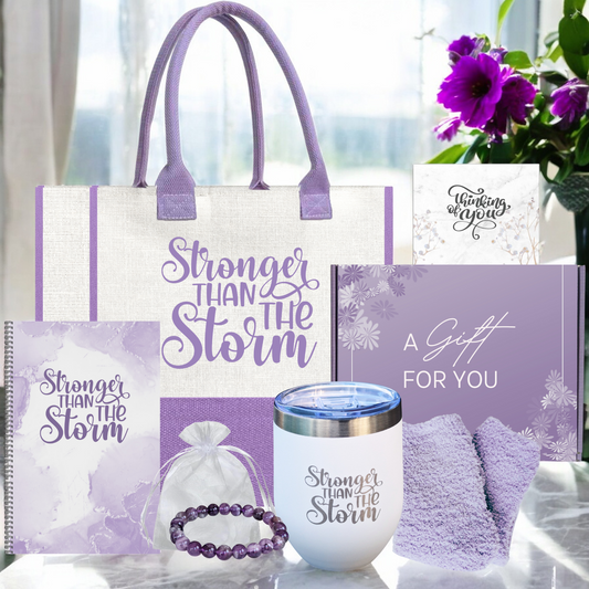 A gift tote bag with 'Stronger Than The Storm' printed, alongside a white insulated tumbler, a purple stone bracelet, cozy socks, a spiral notebook, and a thinking of you card.