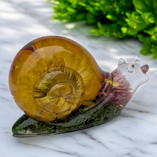 Close-up of resin snail shell showing bi-color Gerbera Daisy and Gomphrena Globosa flowers inside clear resin