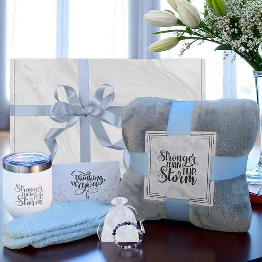 Women's self-care gift box with cozy grey blanket, blue socks, Blue Sodalite stone bracelet, white tumbler and thinking of you card – perfect get well gift for her. Featuring Stronger Than the Storm Theme