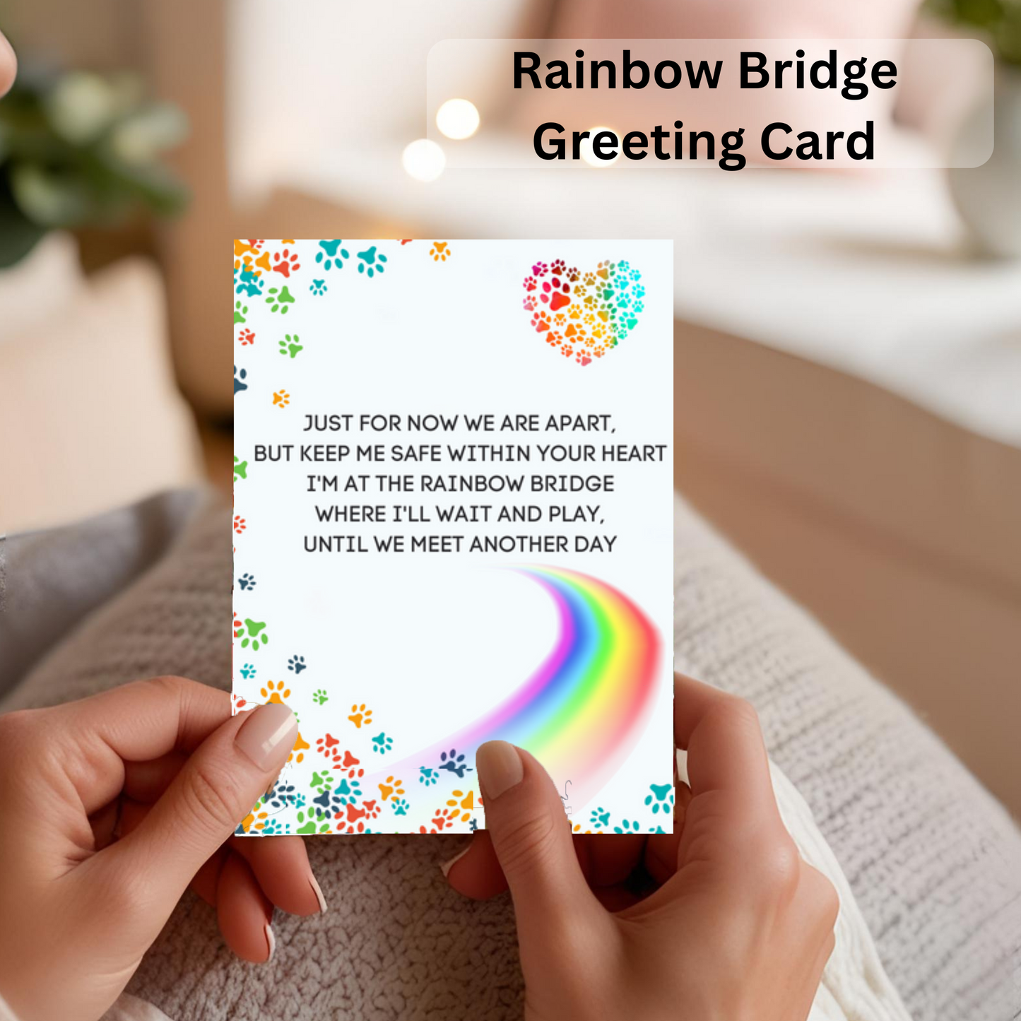 Person holding a Rainbow Bridge greeting card with a rainbow design and text.