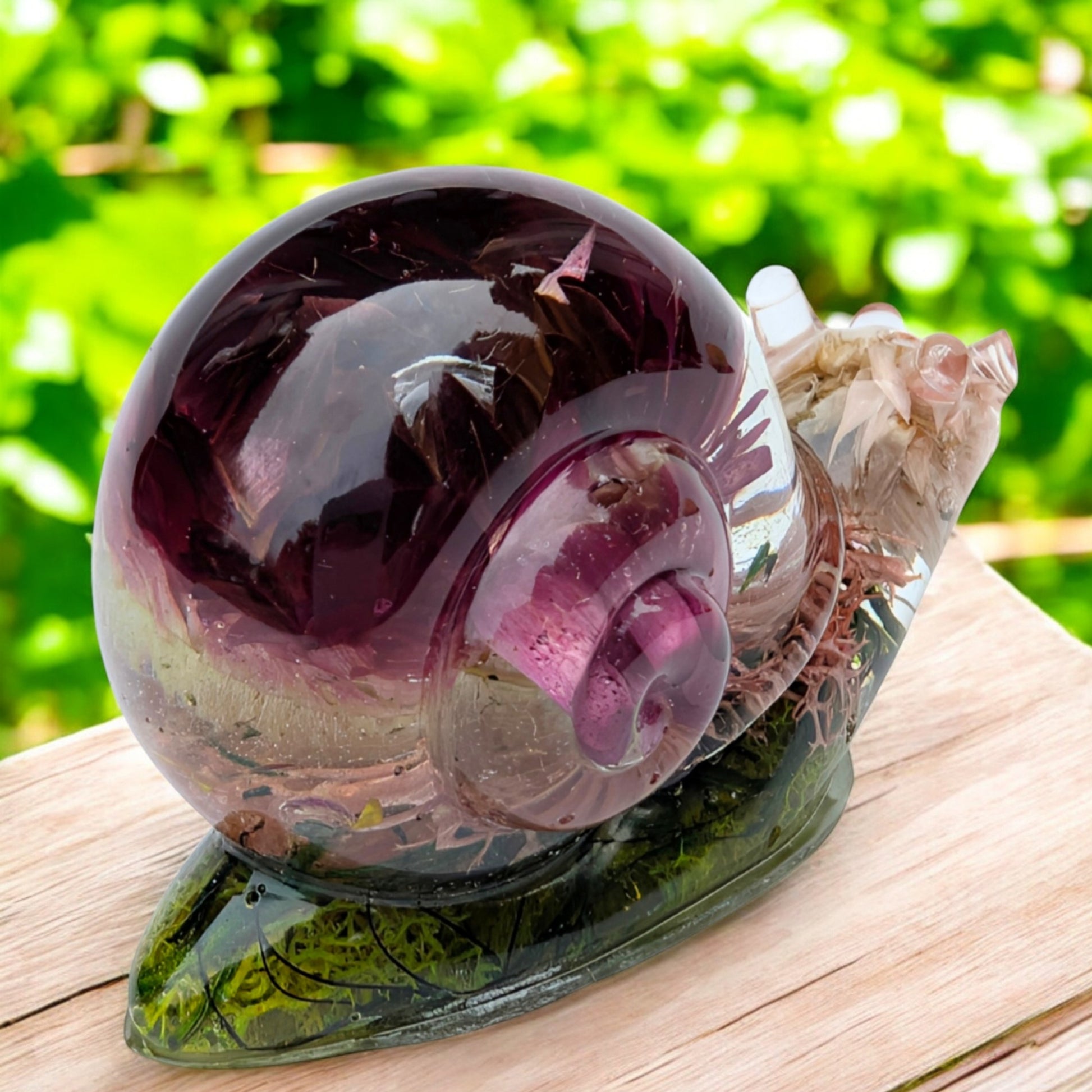 Resin snail figurine displayed on a shelf with plants – handmade nature decor for home or office