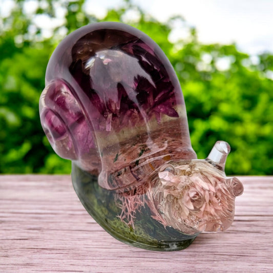Close-up of resin snail shell with real dried flowers and moss, showing glossy clear resin and fine botanical detail