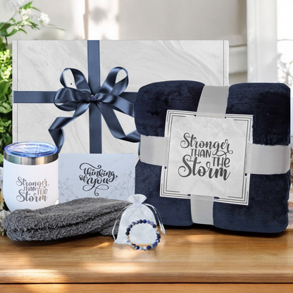 Women's self-care gift box with cozy navy blue blanket, blue socks, blue Sodalite natural stone bracelet, white 18 oz tumbler and thinking of you card – perfect get well gift for her. Featuring Stronger Than the Storm Theme