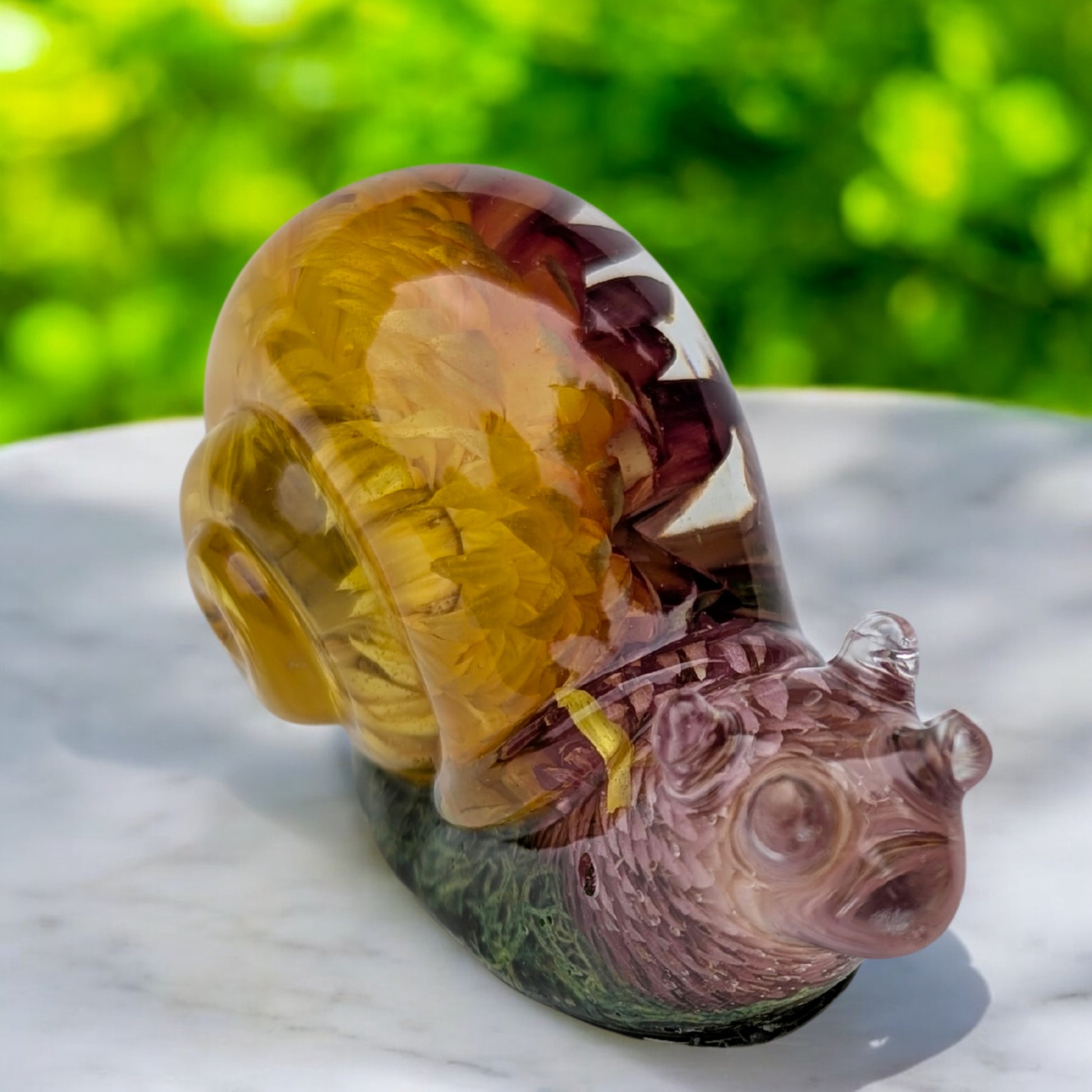 Resin snail figurine with dried flowers and moss displayed on a table – handmade botanical home decor